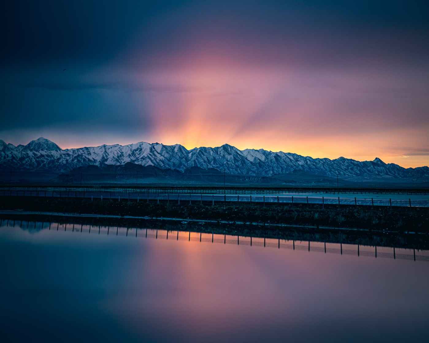 body of water near snow capped mountains