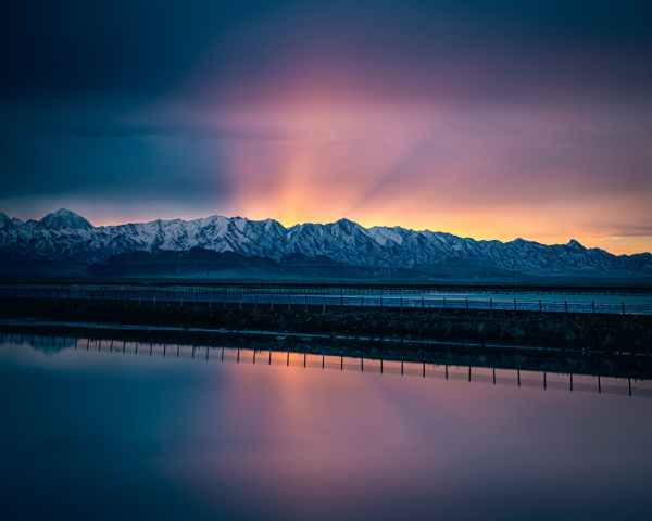body of water near snow capped mountains