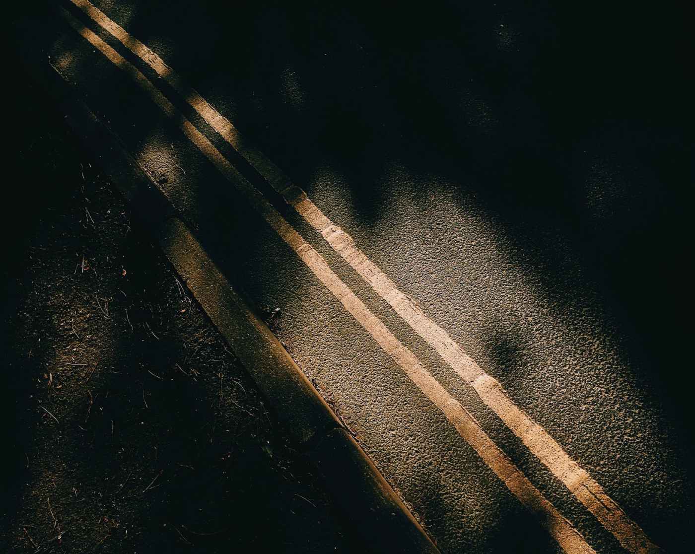 asphalt road with marking lines near soil and shadows